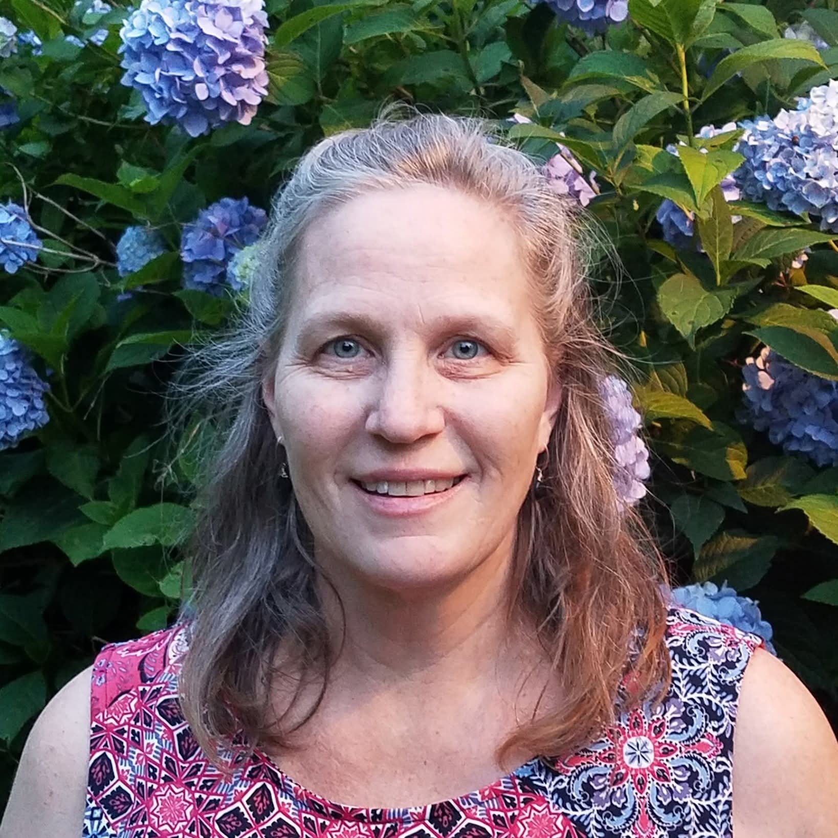 Portrait of Ms. Angie among blue hydrangeas
